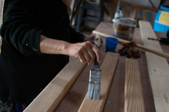 Person painting a plank of wood