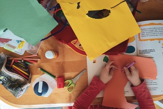 A photo of a child's hand colouring on cut out paper