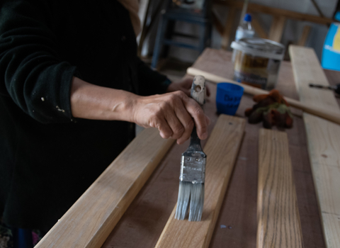 Person painting a plank of wood