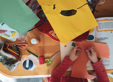 A photo of a child's hand colouring on cut out paper